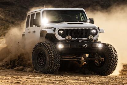 Baja Designs Squadron 2.0 LED light pods mounted on Jeep Rubicon driving through rocky terrain at night