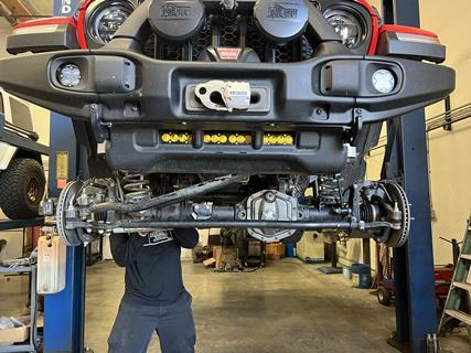 1. With the Jeep up on the lift and the wheels and tires removed, disassembly began. Note the position of the factory tie rod below the centerline of the axle and how the steering stabilizer hands down below the tie rod